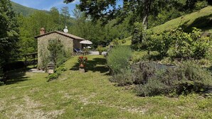 Ein Steinhaus mit Garten, einer überdachten Sitzgelegenheit und einer Satellitenschüssel.