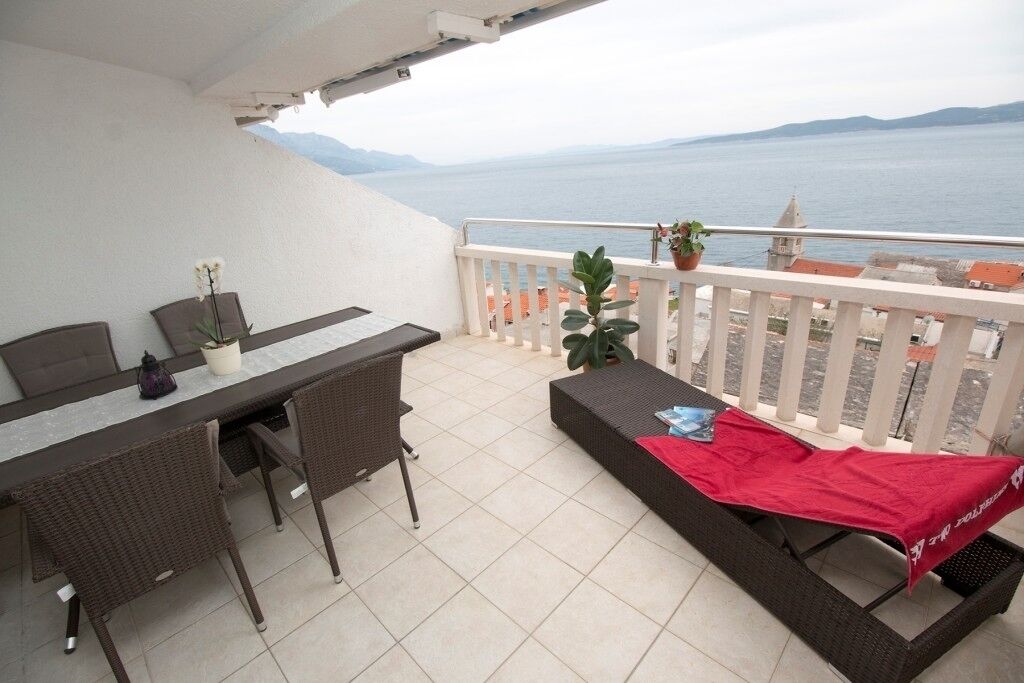 A balcony with a dining table, chairs, and a sofa.