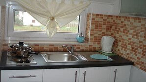 A kitchen with a window, a sink, a stove, and a tiled backsplash.