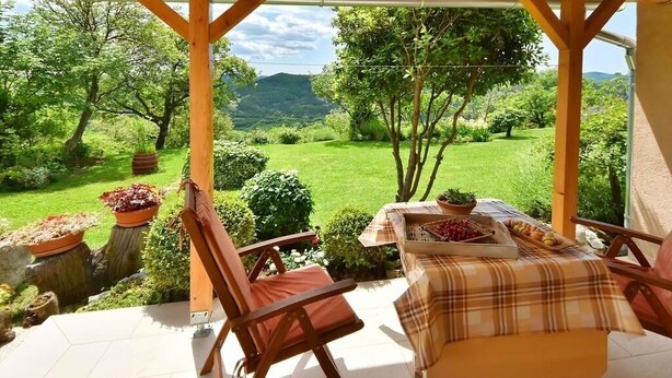 A covered patio with a table set for dining, surrounded by chairs, overlooking a lush garden and distant hills. - Apartment in Roč with Terrace, Air condition, WIFI, Washing machine (4194-2) (Roc)