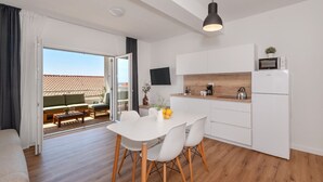 Una cocina moderna con armarios blancos, encimera de madera y microondas integrado.