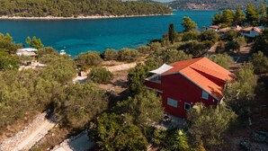 Una propiedad costera con un edificio rojo, vista despejada al mar y vegetación circundante.