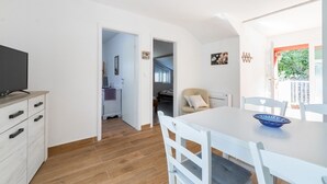 Un espacio habitable pequeño con comedor, un televisor en un mueble de madera y vistas al exterior.