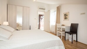 Ein Hotelzimmer mit einem großen Bett, einem Schreibtisch mit Stuhl, einem Kleiderschrank und einer Klimaanlage.