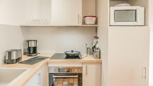 Una kitchenette compacta equipada con tostadora, cafetera, cocina por inducción, horno y microondas.