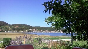A table with a potted plant, red chairs, and a view of a coastal town and hills. - Apartment in Supetarska Draga with Seaview, Balcony, Air condition, WIFI (4325-3) (Supetarska Draga)