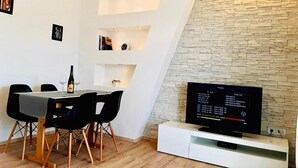 A modern living room with a dining area, a stone accent wall, and a flat-screen TV. - Apartment in Supetarska Draga with Seaview, Balcony, Air condition, WIFI (4325-3) (Supetarska Draga)