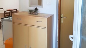 Une cuisine compacte dotée d’un four encastré, d’un petit réfrigérateur et d’un meuble en bois avec des tiroirs.
