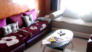 A living room with a sofa, a glass coffee table, and a bed. - Nice apartment in Mozona Beach 4205 (Sidi Rahal)