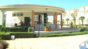 A circular building with a covered patio, columns, and potted plants. - Nice apartment in Mozona Beach 4205 (Sidi Rahal)