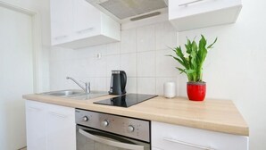 A modern kitchen with white cabinetry, a built-in oven, a sink, and a coffee maker.
