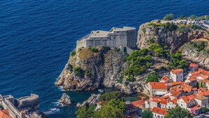 Un pueblo costero con una fortificación histórica en un acantilado con vistas al mar.
