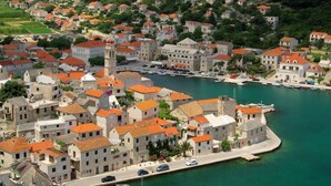 A coastal town with stone buildings, a prominent tower, and a marina with boats. - Apartment in Povlja with Seaview, Terrace, Air condition, WIFI (3419-2) (Povlja)
