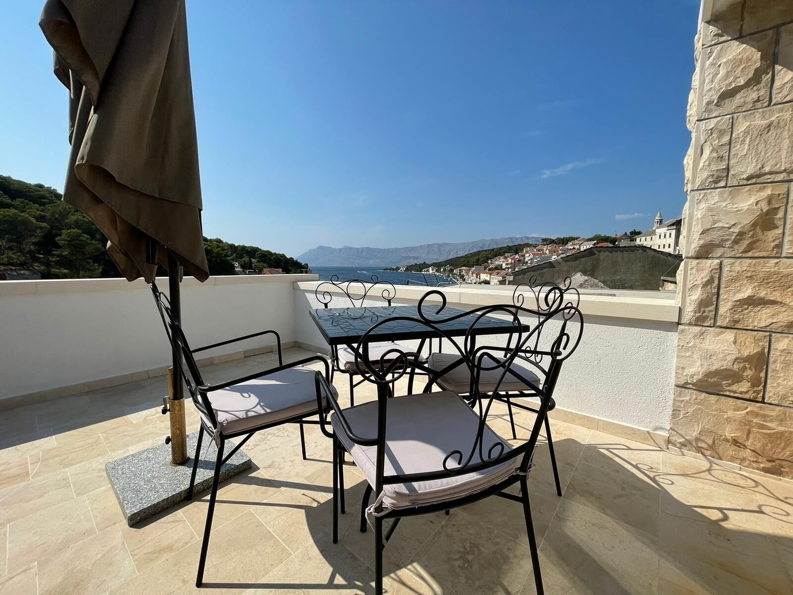 A terrace with a table and chairs, overlooking a coastal view.