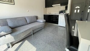 A compact living space with a grey sofa, a kitchenette with black cabinets, and a small dining area. - Apartment in Povlja with Seaview, Terrace, Air condition, WIFI (3419-2) (Povlja)