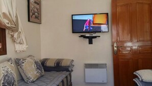 Ett vardagsrum med en soffa, en tv som är monterad på väggen och en dörr av trä.