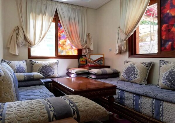 A cozy living room with a sofa set, a wooden coffee table, and a window with curtains.