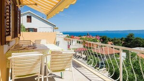 En balkon med et bord og stole, der giver udsigt over kysten.
