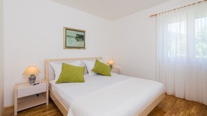 Et soveværelse med en seng, to sengeborde, en lampe, et billede og et vindue med gardiner.