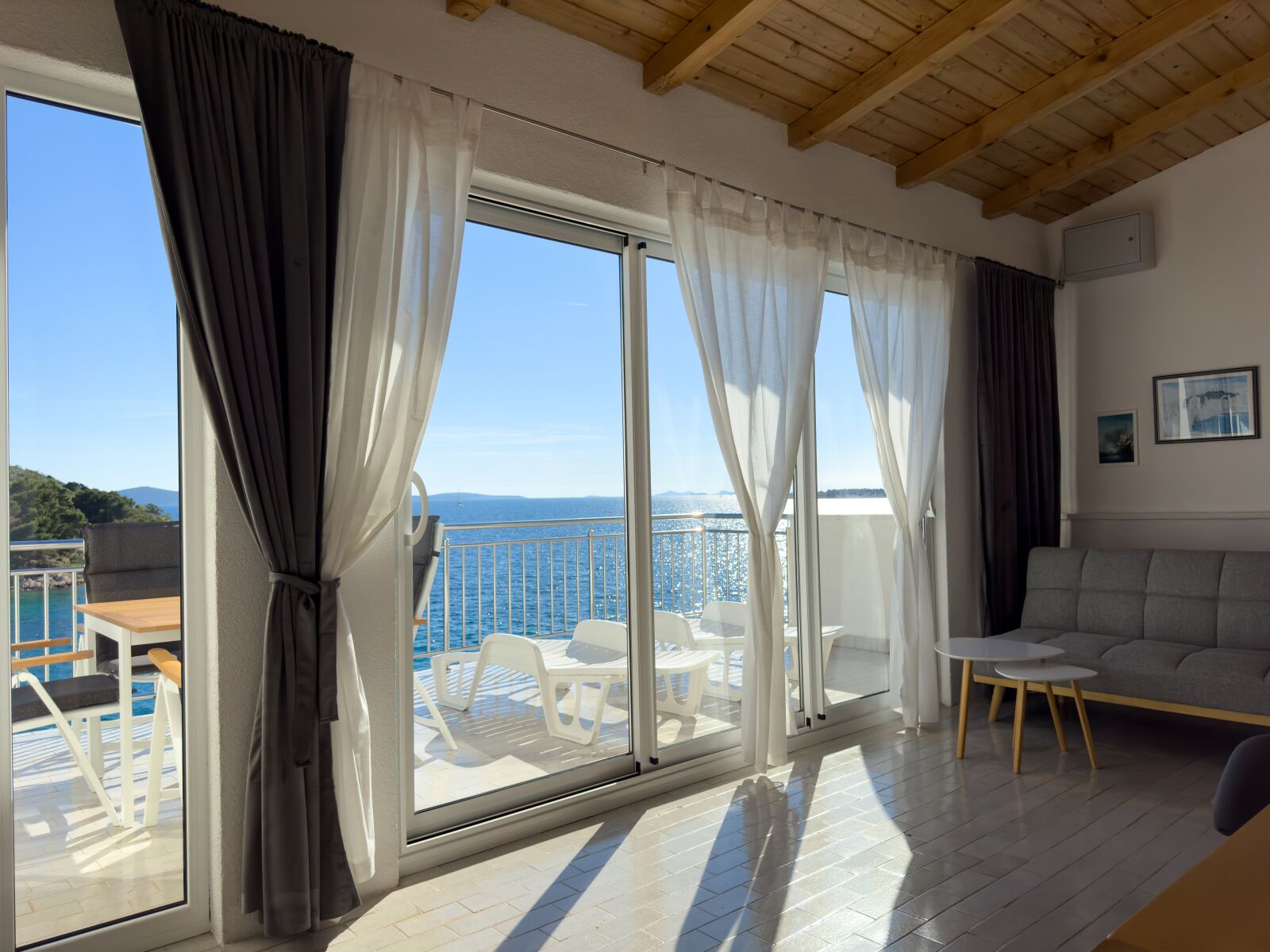 A spacious balcony with a clear view of the sea, a sofa, and a dining table.