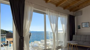En rummelig balkon med krystalklart havudsigt, en sofa og et spisebord.