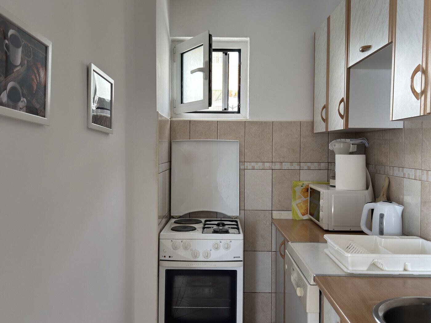 A compact kitchen with a gas stove, oven, and a coffee maker.
