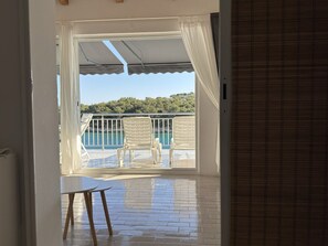 An open balcony with a pool, white chairs, and a table. - Apartment in Tribunj with Seaview, Terrace, Air condition, WIFI (68-2) (Tribunj)