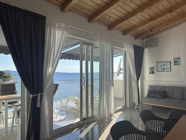 A room with a balcony, a sofa, and a table with chairs.