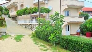 A multi-story residential building with balconies, a stone staircase, and a gravel driveway. - Apartment in Lopar with Balcony, Air condition, WIFI (87-1) (Lopar)