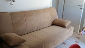 A beige sofa with a cushion, a wall-mounted light, and a door with a sign. - Apartment in Lopar with Balcony, Air condition, WIFI (87-1) (Lopar)