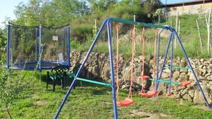 A playground with swings and a trampoline, surrounded by greenery and a stone wall. - Apartment in Lopar with Balcony, Air condition, WIFI (87-1) (Lopar)