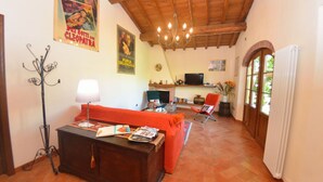 Una sala de estar acogedora con techo de madera, chimenea, televisor y un sofá rojo.