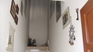 Eine Treppe mit Handlauf, eine Tür auf der rechten Seite sowie Wanddekorationen, darunter gerahmte Bilder und ein Schlüssel.