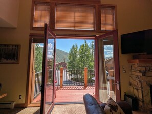 A room with a large sliding glass door leading to an outdoor deck with a view of a mountain and trees. - Gorgeous Mountain Views, Hot Tub (Keystone)