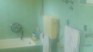 Ein Badezimmer mit zwei Toiletten, einer Badewanne und einem Waschbecken.