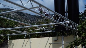 Ein Funktionsbereich mit Metallkonstruktion, einem Wasserschlauch, einem Waschbecken und zwei großen Tanks an einer Wand.