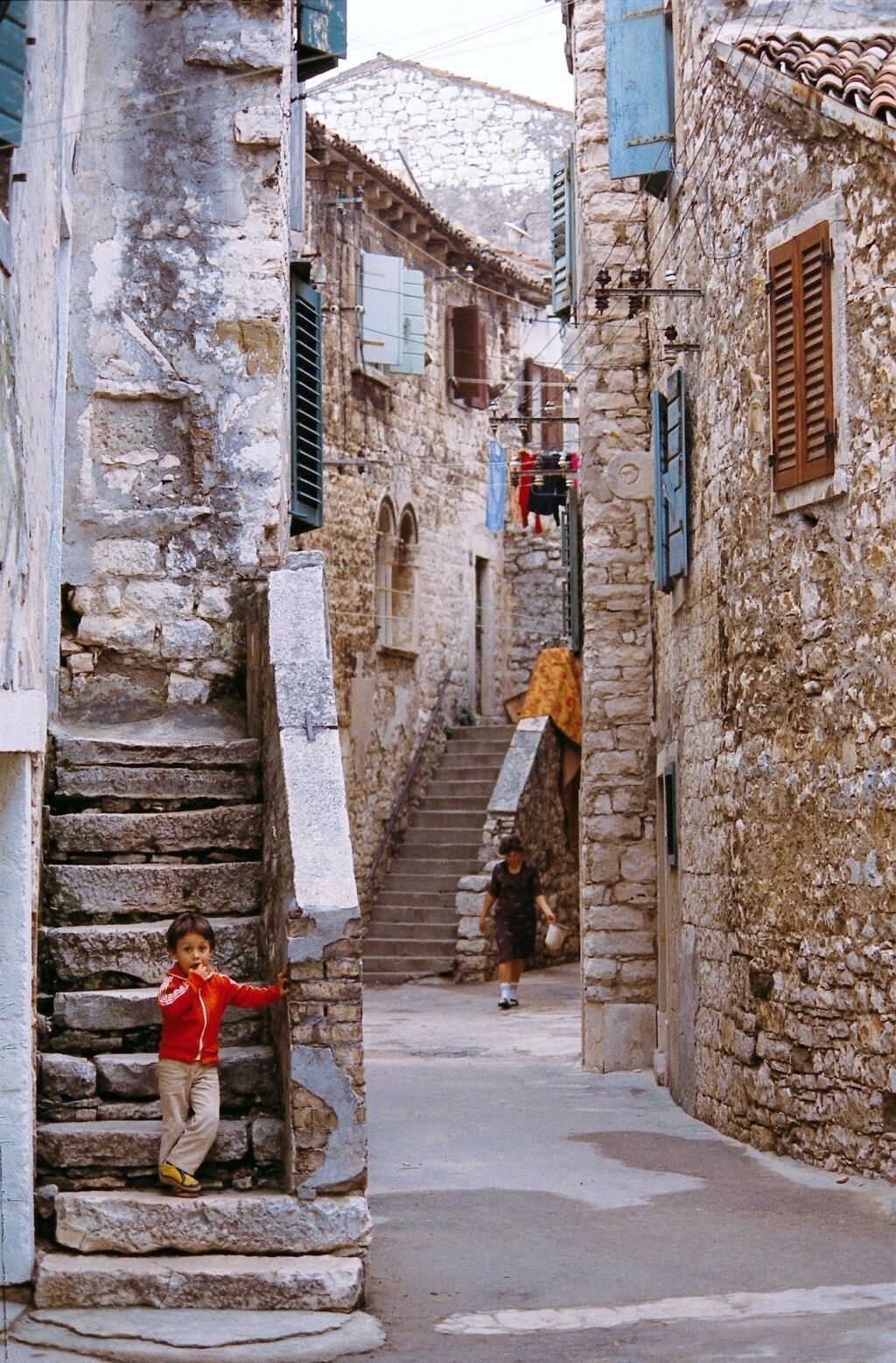 A narrow stone street with a staircase leading to a building.