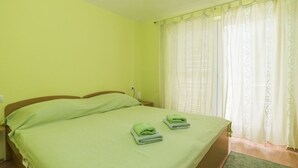 A room with a bed, two folded towels, a nightstand, and a window with curtains. - Apartment in Umag with Balcony, Air condition, WIFI (653-2) (Umag)