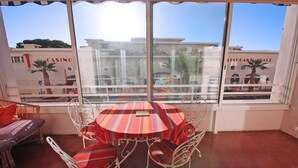 Una habitación con una mesa redonda y sillas, ventanas amplias y vistas a edificios.