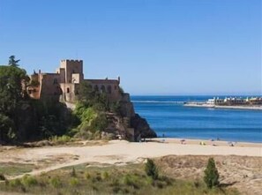 Un castillo costero con una playa al frente.
