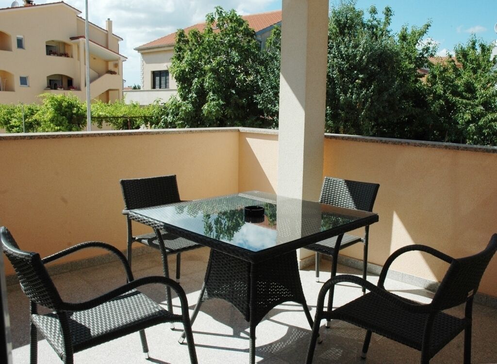 A glass-top table with four chairs on an outdoor balcony.