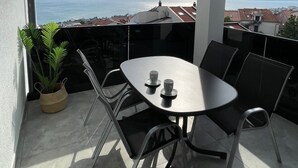 A balcony with a table and chairs, a potted plant, and a view of the sea and buildings. - Apartment in Crikvenica with Seaview, Balcony, Air condition, WIFI (3492-4) (Crikvenica)