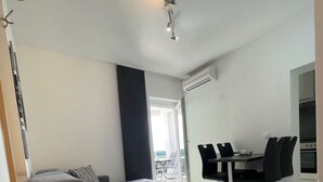 A modern bedroom with a grey sofa bed, a dining area with a table and chairs, and a view through a large window. - Apartment in Crikvenica with Seaview, Balcony, Air condition, WIFI (3492-4) (Crikvenica)