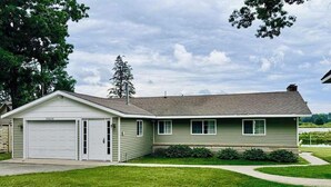 A single-story house with a garage, a front lawn, and a driveway. - Firefly Cottage | West Twin Lake Getaway (Lewiston)