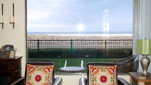 A room with a view of the ocean, a balcony with chairs, and a lamp. - On the Promenade 1st floor. Spectacular Panoramic Ocean Views, Patio with grassy (Seaside)