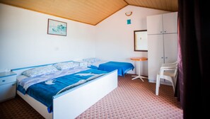 A bedroom with two beds, a small table, a mirror, and a wardrobe.