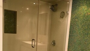 Moderni kylpyhuone, jossa on lasiseinällä varustettu suihku, wc ja pesuallas.