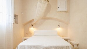 Un dormitorio con una cama, dos mesitas de noche y una lámpara de pared.