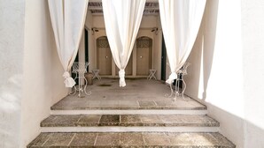 Una escalera de piedra que lleva a un espacio cubierto con cortinas blancas y sillas de metal.
