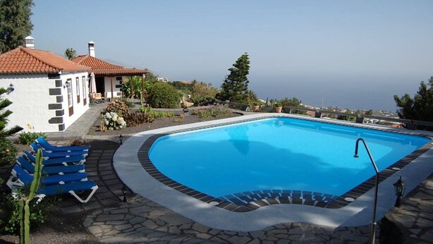 A swimming pool with a stone border, surrounded by lounge chairs and a cactus plant. - Villa de Mazo, La Palma (Villa de Mazo)